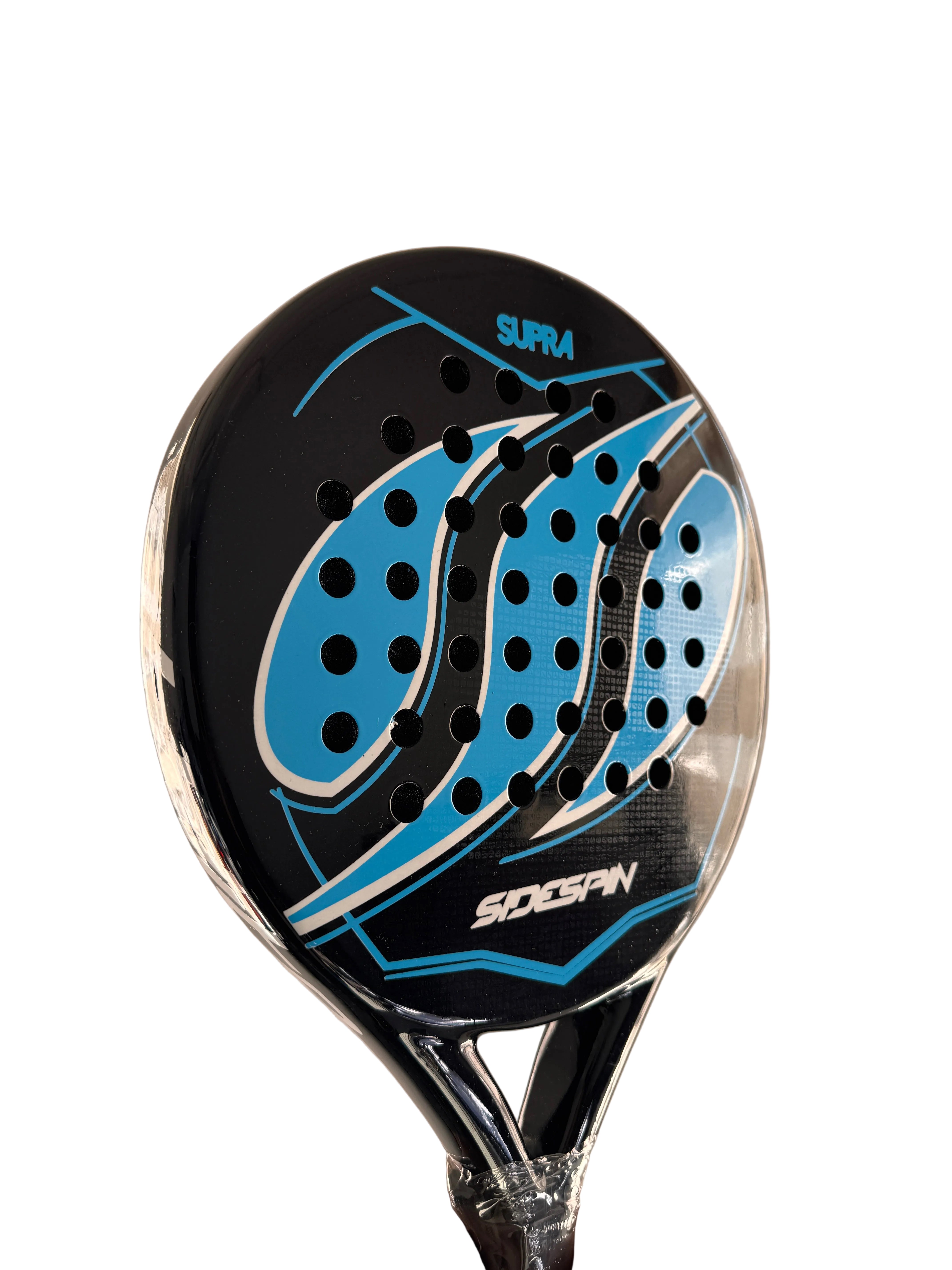 A close-up of a S.P.A.W. padel paddle head with a black, blue, and white graphic design, held by a hand against a beige wall.