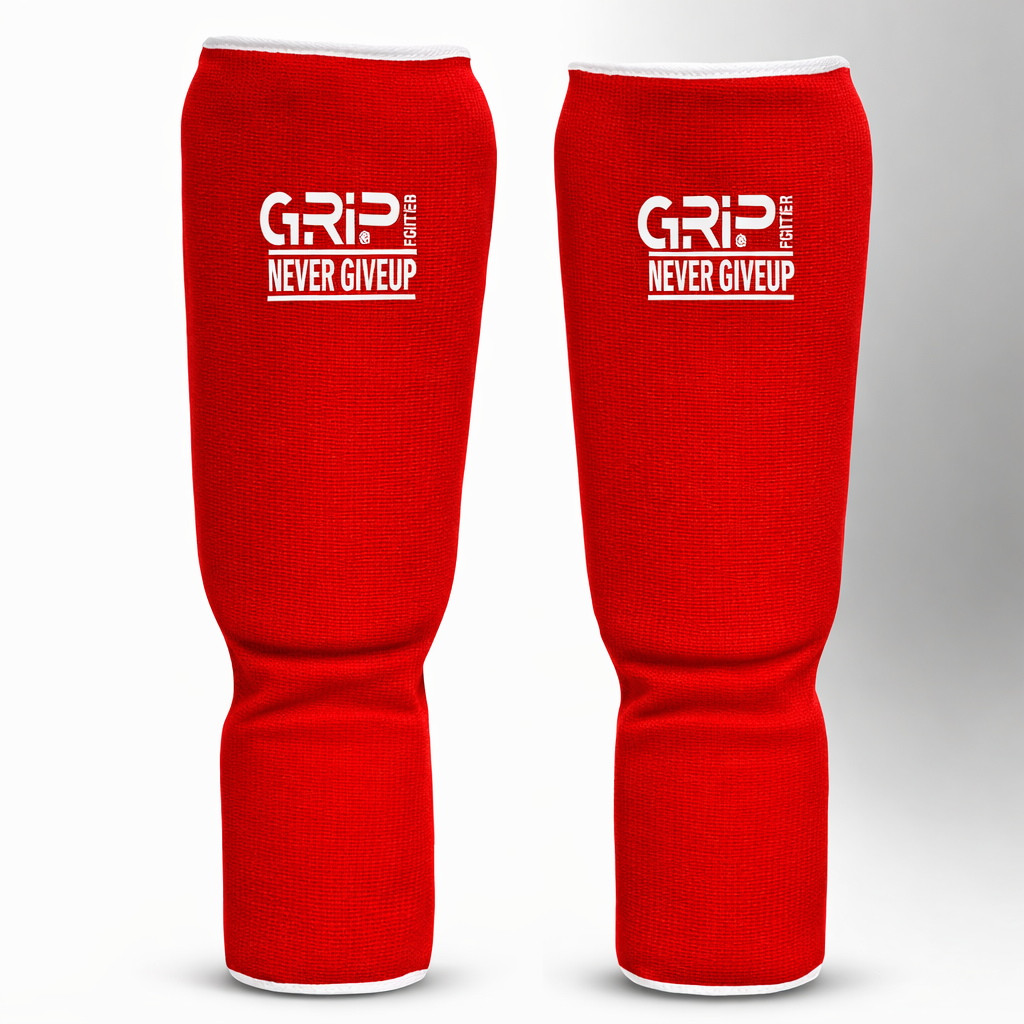 Red GRIP shin guards with “Never Give Up” logo on a white and grey background.
