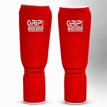 Red GRIP shin guards with “Never Give Up” logo on a white and grey background.